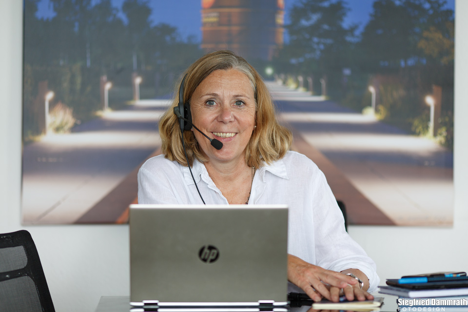 Frau mit Headset vor einem Laptop