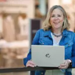 Blonde Frau mit einem Laptop in einem Einkaufszentrum