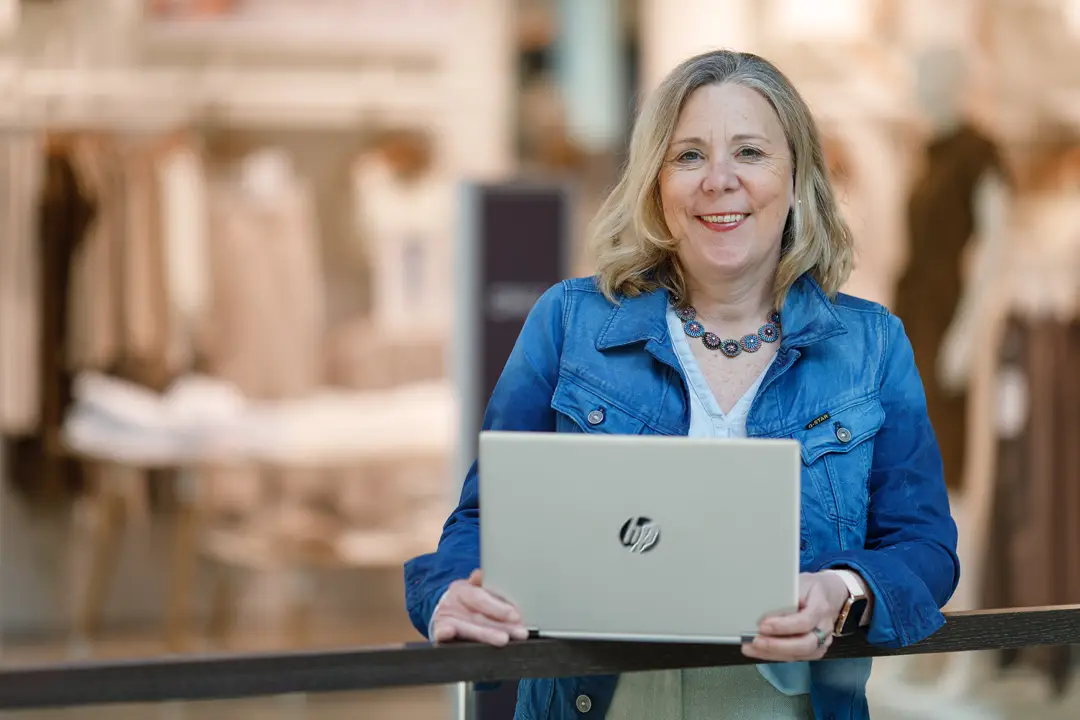 Blonde Frau mit einem Laptop in einem Einkaufszentrum