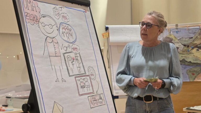 Blonde Frau mit Brille präsentiert am Flipchart