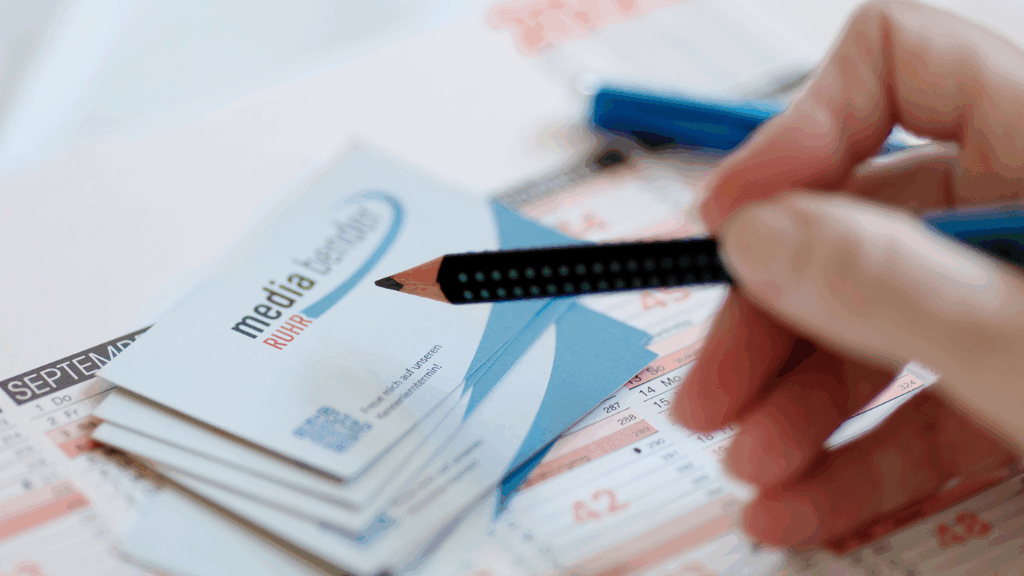 Bleistift mit Visitenkarten und Kalender zur Businessplanung.