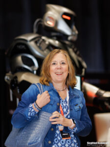 Symbolbild zum Thema Menschlichkeit und KI: Nicole Bender vor einem Roboter.